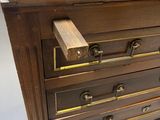 a wooden chest of drawers with brass hardware on it