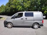 a silver van parked in a parking lot with trees in the background