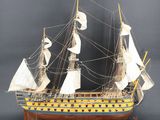 une vieille maquette en bois représentant un voilier posée sur une surface grise