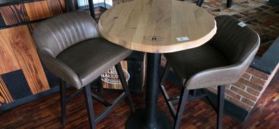 leather bar stools and a round wooden table in a restaurant