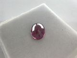 a close up of a pink sapphire stone on a white surface