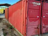 a red shipping container sitting in the middle of a dirt field