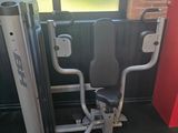 Vue depuis l'entrée d'une salle de sport équipée d'un banc, d'appareils de musculation et d'une fenêtre