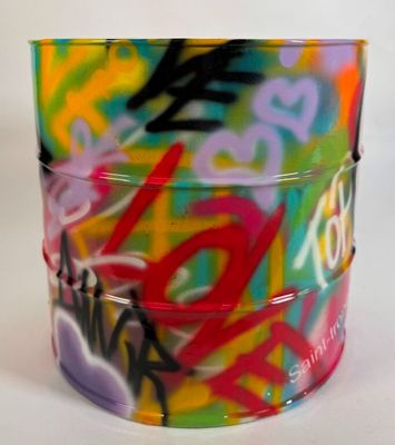 une tasse colorée ornée de graffitis, posée sur une table