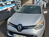 La voiture argentée est garée devant un immeuble dont le mur est recouvert de graffitis.