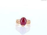 an image of a ring with a red stone on a white surface