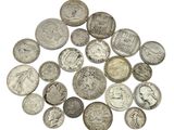 a pile of old silver coins on a white surface