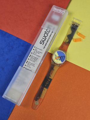 a watch and a pen sitting on a colorful surface