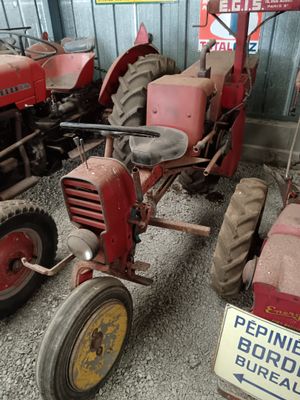 several old tractors are parked in a row in a garage