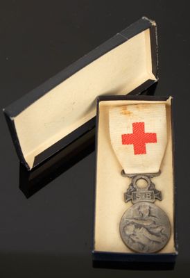 une médaille d'argent dans une boîte ornée d'une croix rouge