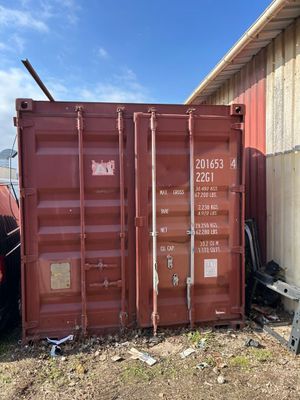 a red shipping container sitting on top of a field next to a building