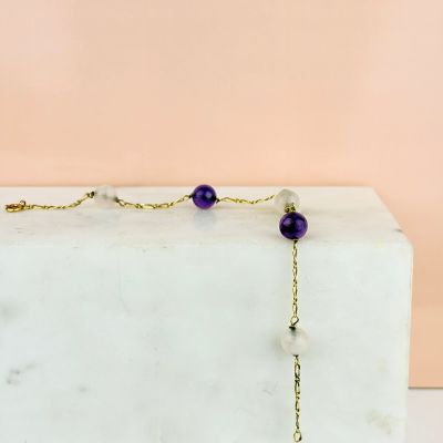 un gros plan d'un collier violet et blanc posé sur un bloc de marbre
