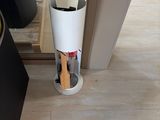 a white vase with a wooden spoon in it sitting on the floor