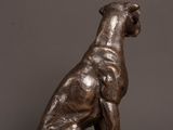 a bronze statue of a dog sitting on top of a wooden table