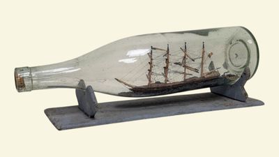 un bateau dans une bouteille en verre posée sur un socle