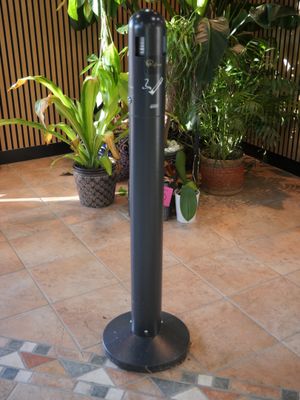 a black pole with a clock on it on a tiled floor