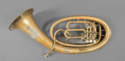 an antique brass french horn on a grey background