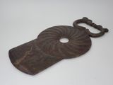 une vieille clé en forme de coquillage posée sur une surface blanche