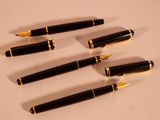 four pens are lined up on a table with a white background