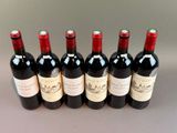 six bottles of red wine lined up in a row on a table