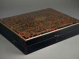 an antique black and gold box with a floral design on the lid
