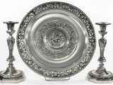 un plateau en argent et deux bougeoirs en argent posés sur une table