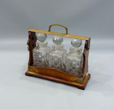 une carafe en verre à l'ancienne, avec un socle en bois et une poignée en laiton