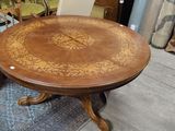 une table dont le plateau en bois est orné d'un motif floral