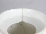 a white vase with a gold rim sitting on a table