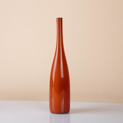 an orange vase sitting on top of a white table next to a wall
