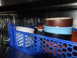 a blue basket filled with dishes and bowls on top of a counter