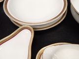 a lot of white and gold plates and bowls on the table