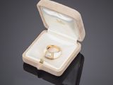 une bague en or dans une boîte blanche posée sur une surface noire