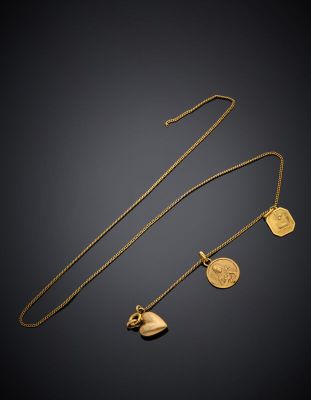 a gold necklace with a heart and two charms on it