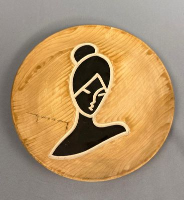 une assiette en bois sur laquelle est représentée une femme