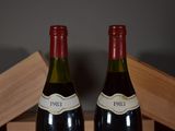 two bottles of red wine sitting on top of a wooden table