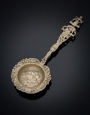 an ornate silver spoon with a handle and handle on a black surface