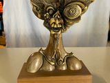 une statue en bronze représentant une créature, posée sur un socle en bois
