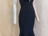 Une femme en robe noire se tient à côté d'un mannequin