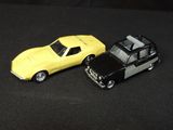 two toy cars sitting next to each other on a black surface