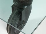 a glass table with a metal caste and a glass table top