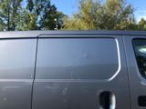 a silver van parked in a parking lot with trees in the background