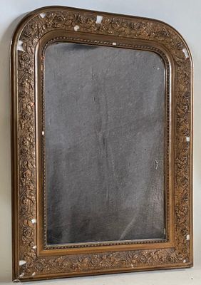 Un vieux miroir est posé sur une étagère, près d'un mur blanc.