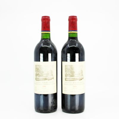 two bottles of red wine sitting next to each other on a white surface