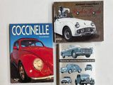 trois livres posés sur une table blanche, avec une voiture rouge et blanche et une autre voiture rouge et blanche
