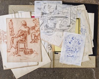 une pile de dessins posée sur une table, à côté d'un stylo et d'une feuille de papier