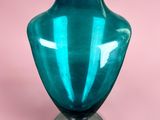 a blue glass vase sitting on top of a metal stand