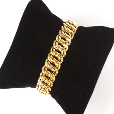 un gros plan d'un bracelet à maillons dorés posé sur un coussin noir