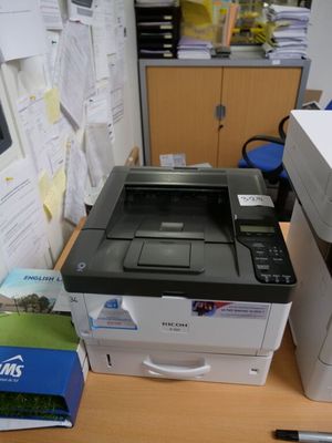 a printer sitting on top of a desk next to a stack of papers