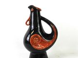 a black and orange vase on a black stand